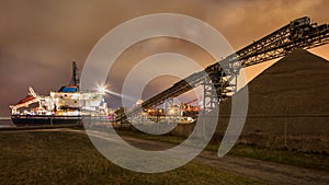 Anchored barge unloading gravel at night