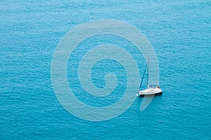 Anchored yacht with retracted sails in the Mediterranean sea.