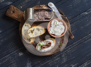 Anchovy and goat cheese sandwich on rustic wooden board