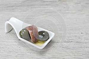 Anchovy and olives in a china spoon