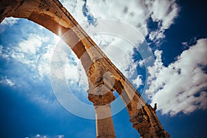 Ancien stone arc on the background of sunny, cloudy sky