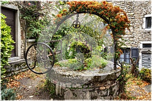 An ancient abandoned well decorating with flowers in medieval village Perouges, France