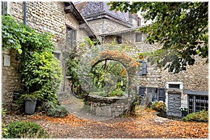 An ancient abandoned well decorating with flowers in medieval village Perouges, France