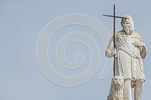 Ancient aged sculpture of poor stranger pilgrim with cross and sitting lion at roof of Santa Maria Assunta Jesuits Church in