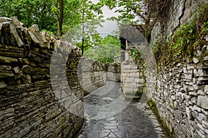 Ancient alleyway with stone-stacked walls in cloudy spring