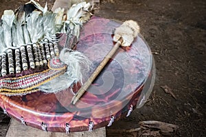 Ancient amerindian tambourine, drum drumstick replica and a feather headdress. photo