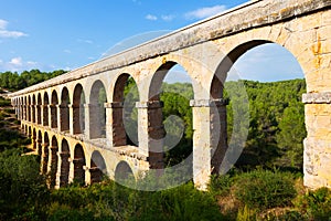 Ancient aqueduct in summer forest. Tarragona