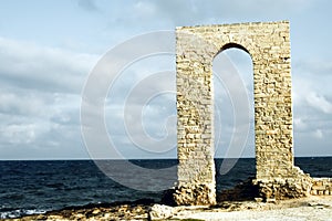 Ancient arch - ruins over seashore, front view