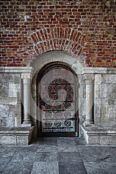 Ancient arched wooden door of the fortress wall, with columns