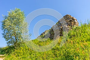 Ancient architectural attractions ruins overgrown with green grass against blue sky in sunny summer day. Background for travel,