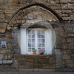 Ancient architecture FaÃ§ade of stone bricks with white window and flowers Brantome France