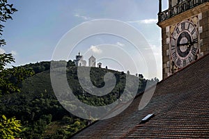 An ancient astronomical clock overlooking the opposite hill with a white chapel