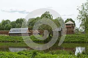 Ancient authentic wooden houses in Belarus, a cloudy day, calm river in landscape