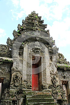 Ancient Balinese carved stone temple entrance with red door