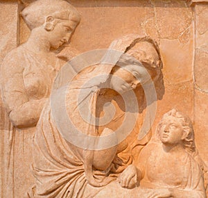 Ancient bas-relief depicting young seated woman with boy and maiden stands in background on ancient Greek funerary stele from