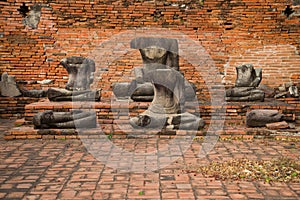 The ancient beheaded Buddha sculptures at a brick wall of the ancient Buddhist temple. Ayutthaya, Thailand