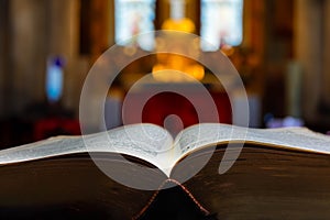 Ancient bible with a soft focus Catholic Christian alter in the background