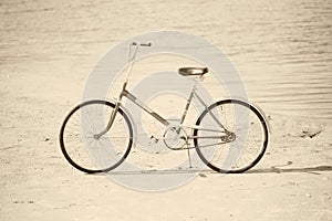 Ancient bicycle on beach - retro sepia