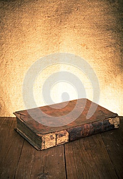 Ancient book on the old wooden table. Toned