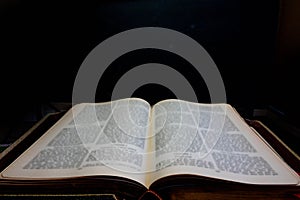 Ancient book which leads to infinity against a black background with soft focus text