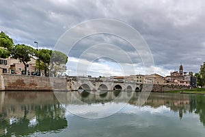 The ancient Bridge of Augustus and Tiberius is reflected in the water of the canal in the historic center of Rimini, Italy
