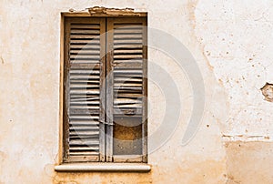 Ancient broken wooden window shutter with rustic stucco wall background