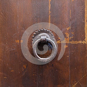 Ancient bronze round knocker on old brown door