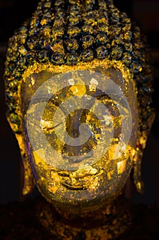 Ancient Buddha face with gold leaf