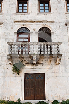 An ancient building with a pillared balcony and Venetian windows.