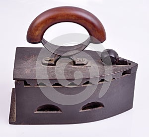 An ancient cast-iron inoculum with a wooden handle on a white background