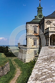 Ancient castle with a stone wall and towers on the background of a beautiful landscape.