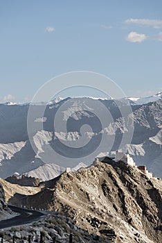 Ancient casttle on cliff among high mountains and bending road