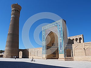 Ancient city under blue sky: square with minaret tower and mosque entrance