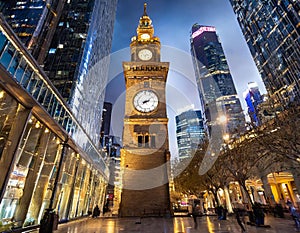 Ancient clock tower stands majestic amidst modern skyscrapers in a bustling city