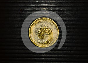 An ancient coin with a nominal value of 500 rupiah from Indonesia on a black background
