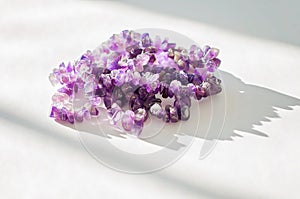Ancient colorful healing crystals or gemstones on a white background: Amethyst necklace bring positive energy, inner peace and