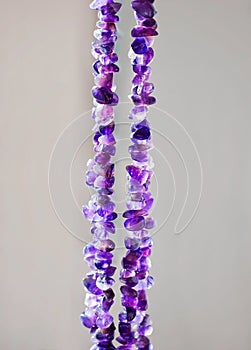 Ancient colorful healing crystals or gemstones on a white background: Amethyst necklace bring positive energy, inner peace and