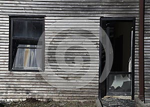 Ancient cracked glass window, doorway in wooden wall made from lapped boards. Antique glasses door. exterior of old house,