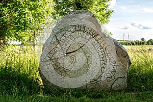 Ancient and cracked rune stone with summer background