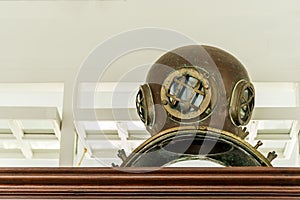 Ancient diving brass helmet equipment with air supply ship on wooden cabinet the interior collection