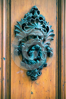 Ancient door knocker on a wooden door in Florence