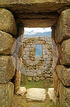 Ancient doorway with the remains of the Incas and the mountain ranges, Machu Picchu, Cusco, Peru