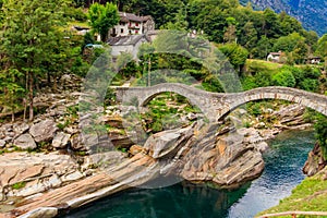 Ancient double arch stone Roman bridge (Ponte dei Salti) over clear water of the Verzasca river in Lavertezzo