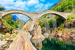 Ancient double arch stone Roman bridge (Ponte dei Salti) over clear water of the Verzasca river in Lavertezzo
