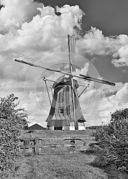 Ancient windmill with thatched roofing in a field with dramatic shaped clouds, The Netherlands