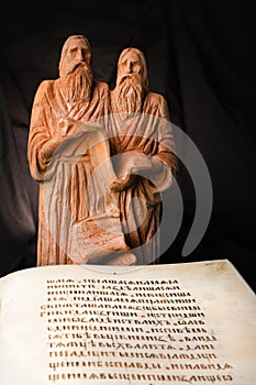 Ancient educators Cyril and Methodius clay statues with antiquarian Bible book with old script. Old christian missionaries for