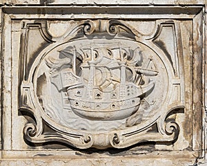 Ancient engraved stone relief in Lisbon with a sailboat and two ravens/