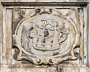 Ancient engraved stone relief in Lisbon with a sailboat and two ravens/