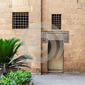 Ancient external old decorated bricks stone wall with two windows and opened door photo