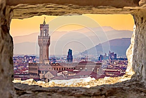 Ancient Florence cityscape and Palazzo Vecchio sunset view through stone window